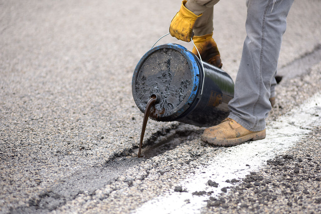 Adam Gaggens fills a pothole with oil